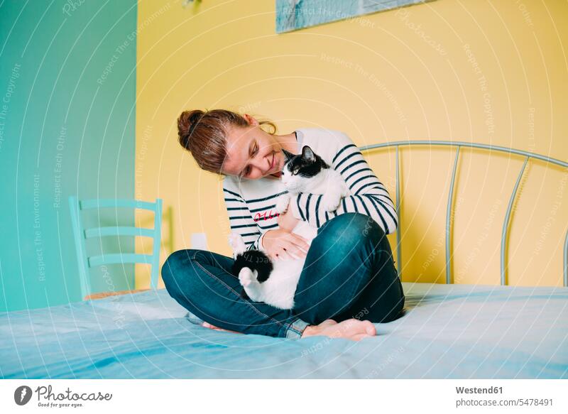 Happy woman with a black and white cat on the bed cats lovely animals animal-loving fond of animals love of animals females women close closeness propinquity
