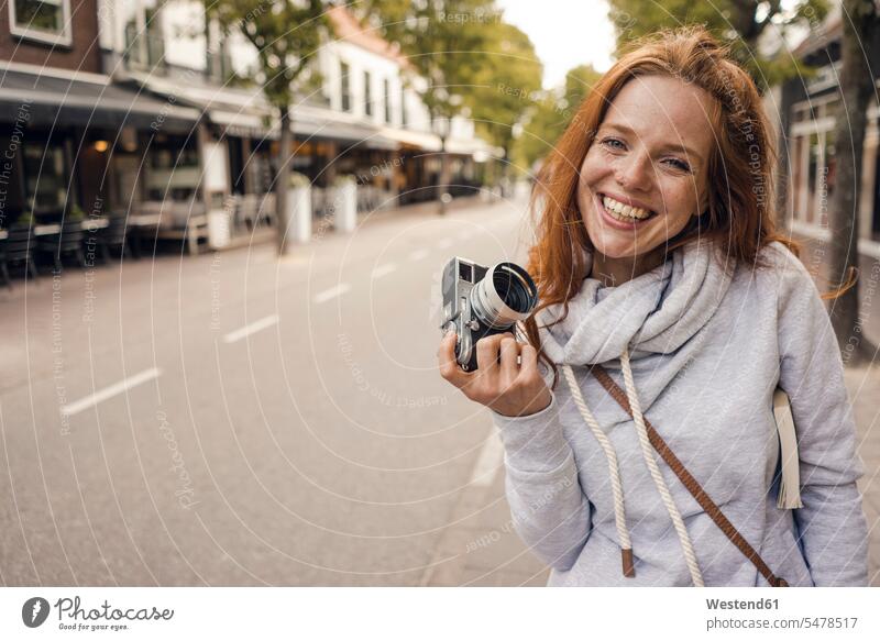 Redheaded woman using analogue camera cameras females women urban urbanity photographing redheaded red hair red hairs red-haired Adults grown-ups grownups adult