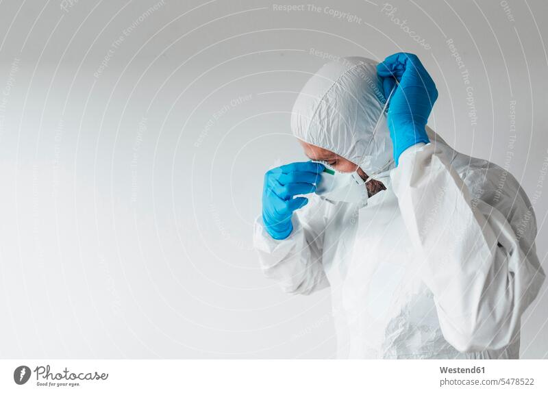 Doctor wearing protective wear, putting on mask (value=0) Occupation Work job jobs profession professional occupation gloves At Work hold White Colors health