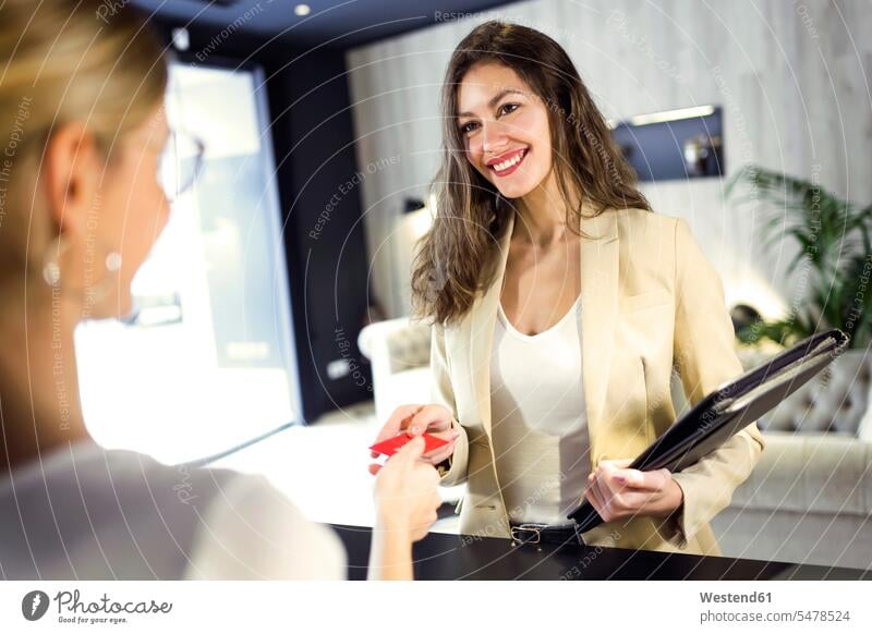 Smiling businesswoman handing over credit card at reception human human being human beings humans person persons client clientele clients customers Occupation