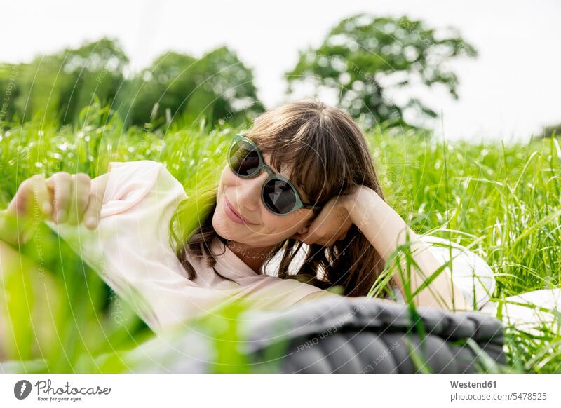 Relaxed woman lying on a meadow reading a book human human being human beings humans person persons caucasian appearance caucasian ethnicity european 1