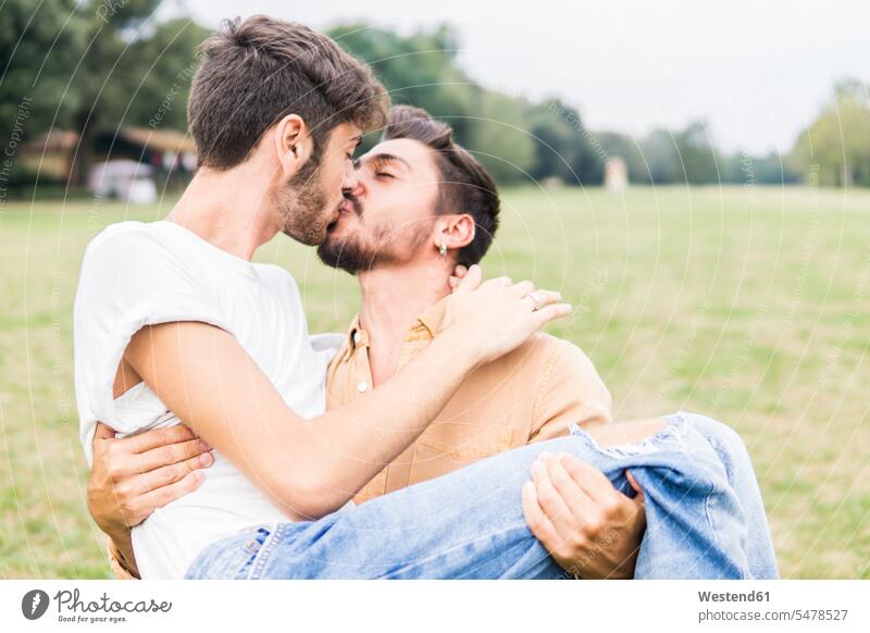 Kissing young gay couple in a park kissing kisses parks gay men gay man homosexual men homosexual man twosomes partnership couples queer same-sex homosexually