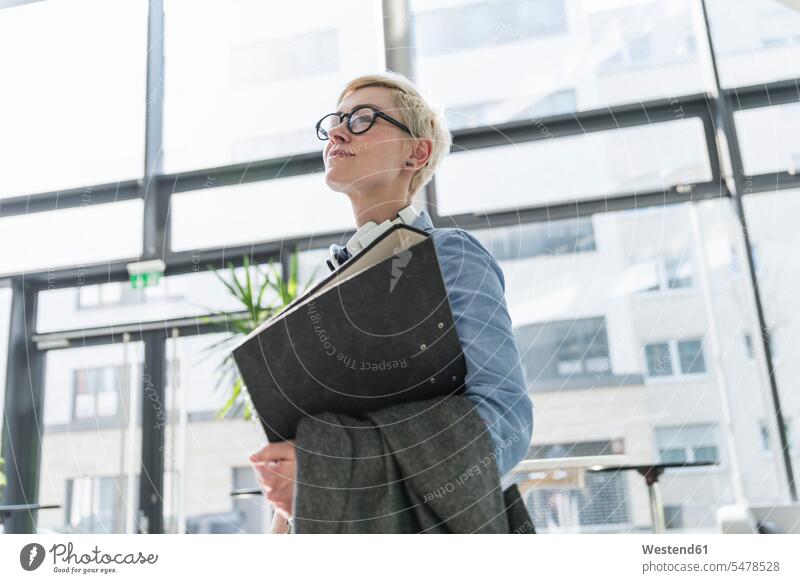 Smiling woman in office building carrying file folder females women office buildings folders documents Adults grown-ups grownups adult people persons