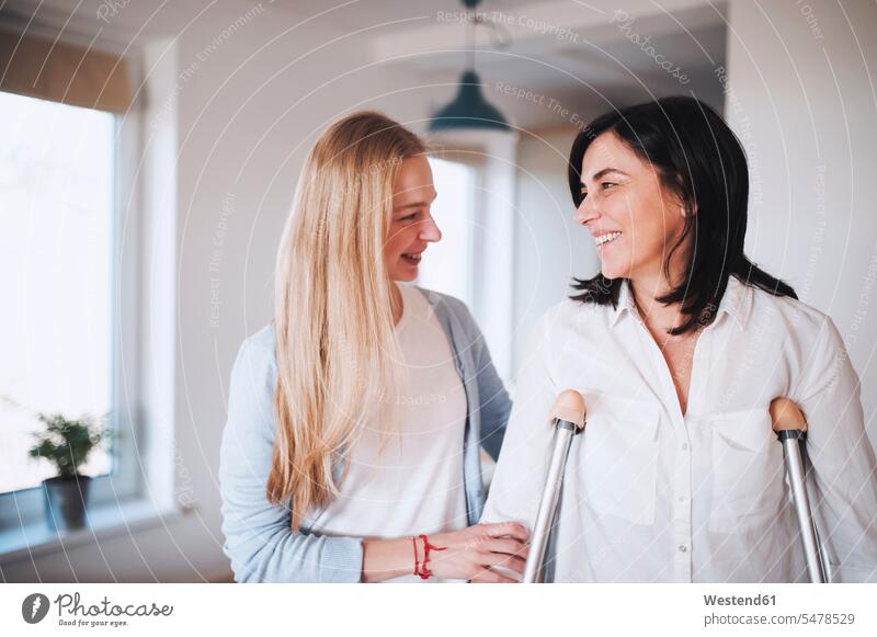 Daughter helping her mother to walk with crutches human human being human beings humans person persons caucasian appearance caucasian ethnicity european adult