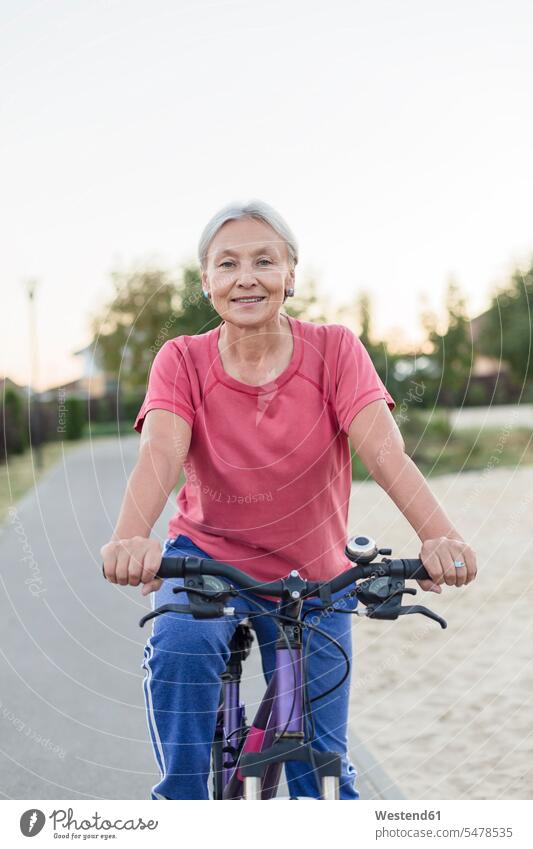 Portrait of smiling senior woman riding bicycle senior women elder women elder woman old bikes bicycles smile riding bike bike riding cycling bicycling pedaling