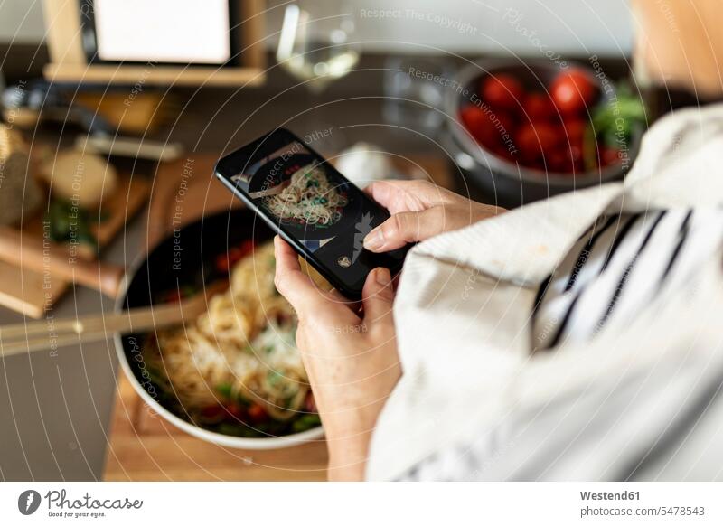 Close-up of woman taking smartphone picture of her pasta dish in kitchen at home human human being human beings humans person persons celibate celibates singles