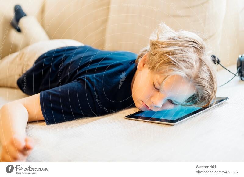 Boy lying on tablet on couch taking a nap T- Shirt t-shirts tee-shirt couches settee settees sofa sofas headphone headset telecommunication headsets asleep