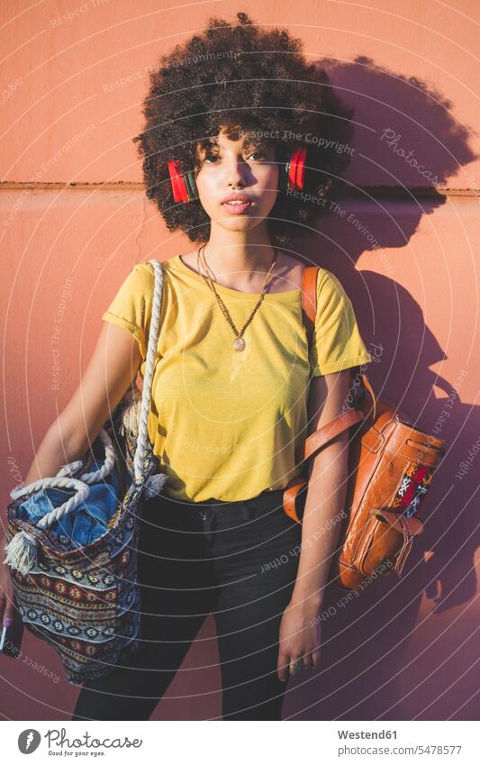 Portrait of young woman with afro hairdo listening to music with headphones human human being human beings humans person persons curl curled curls curly hair