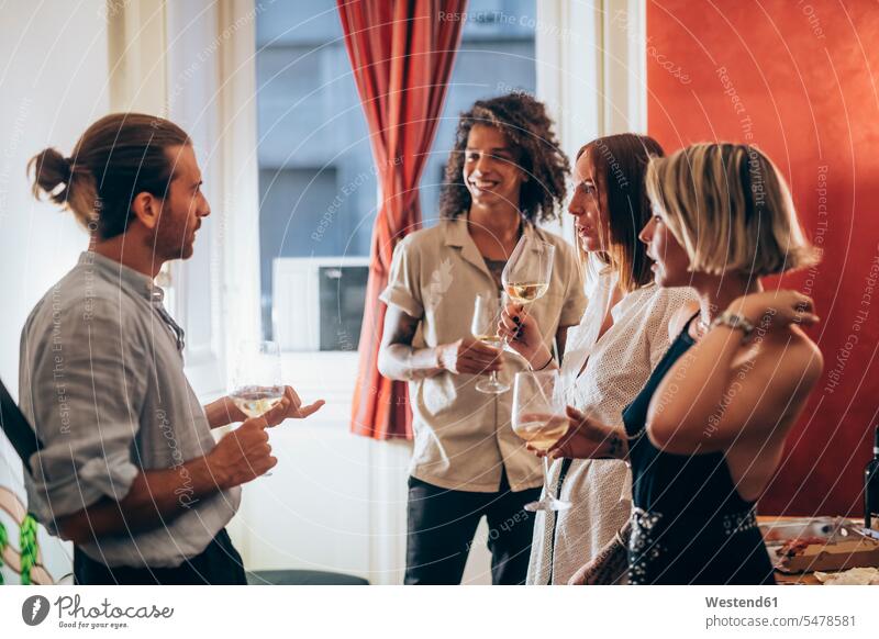 Man and women listening to male friend while drinking wine during party color image colour image indoors indoor shot indoor shots interior interior view