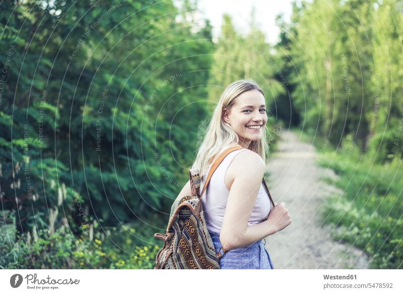Portrait of smiling young woman with backpack on forest track back-pack back-packs backpacks rucksack rucksacks relax relaxing smile hike hiking - trekking