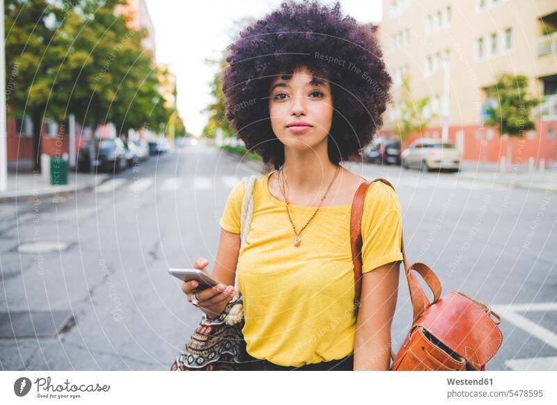 Portrait of confident young woman with afro hairdo in the city human human being human beings humans person persons curl curled curls curly hair back-pack
