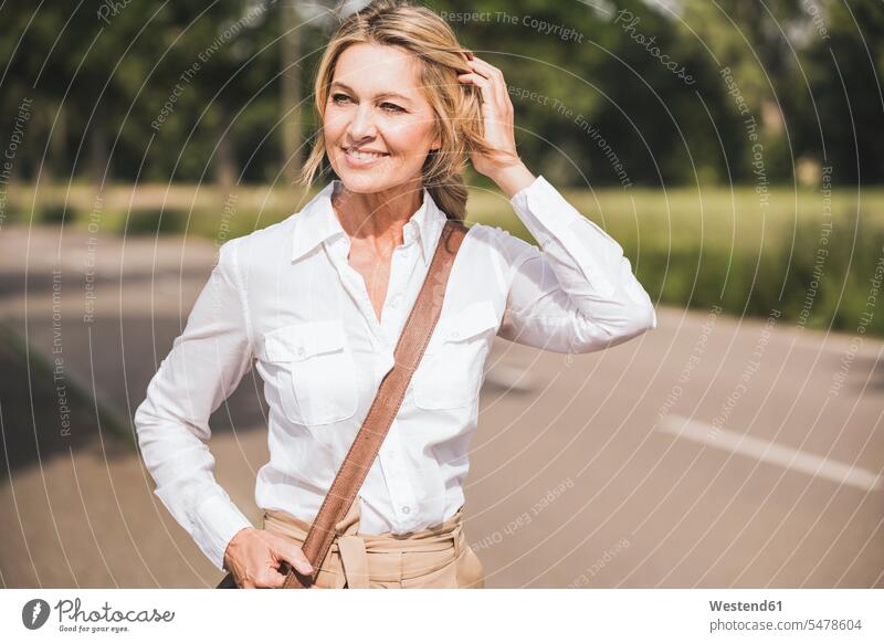 Thoughtful businesswoman carrying shoulder bag on road color image colour image outdoors location shots outdoor shot outdoor shots day daylight shot