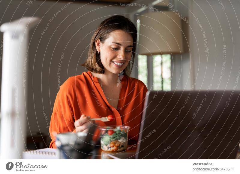 Smiling business person eating salad at home color image colour image indoors indoor shot indoor shots interior interior view Interiors day daylight shot