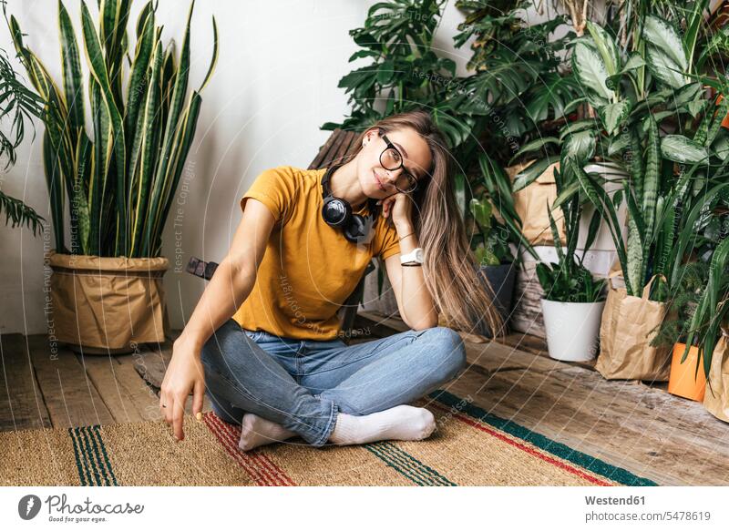 Portrait of relaxed young woman sitting on the floor at home T- Shirt t-shirts tee-shirt headphone headset Eye Glasses Eyeglasses specs spectacles carpets rug