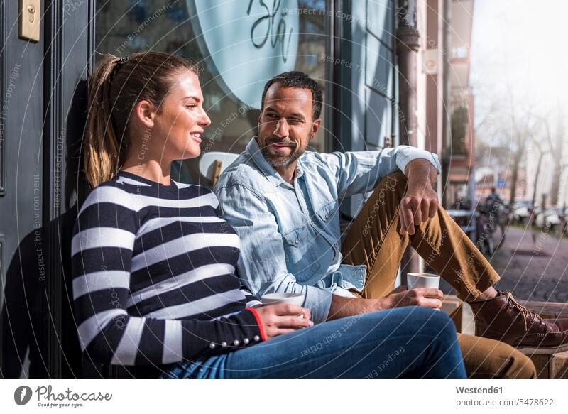 Man and woman sitting outside a cafe talking couple twosomes partnership couples speaking Seated people persons human being humans human beings Joy enjoyment