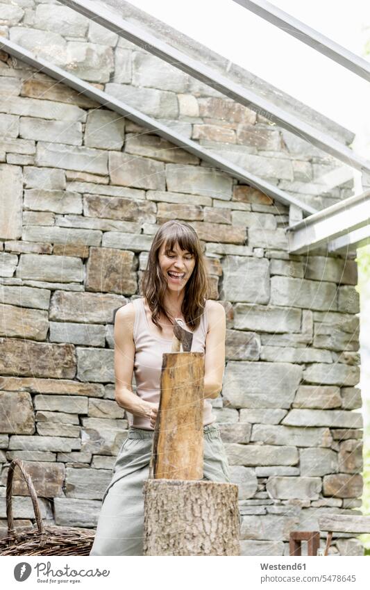 Screaming woman chopping wood in front of a house human human being human beings humans person persons caucasian appearance caucasian ethnicity european 1