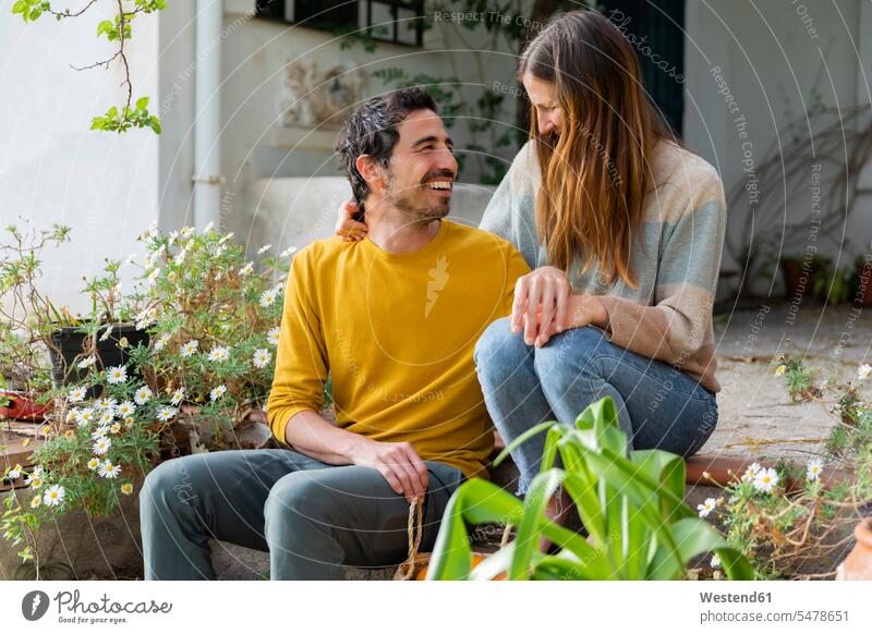 Happy couple talking while sitting on steps against farmhouse color image colour image Spain leisure activity leisure activities free time leisure time