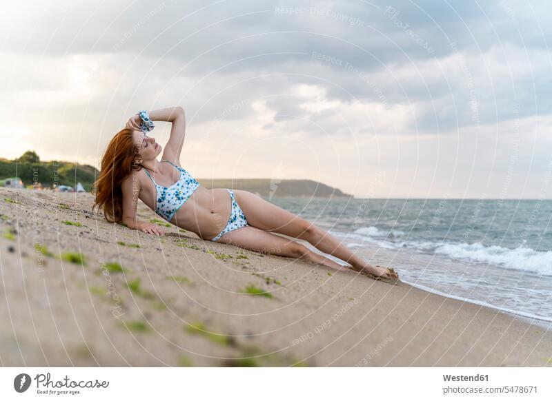 Beautiful young woman wearing bikini lying on beach stock photo