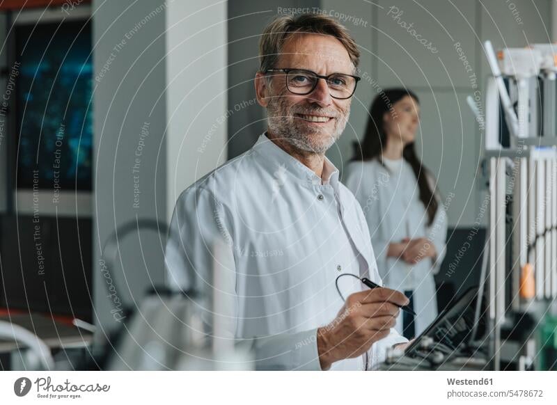 Scientist inventing machinery with female colleague in background at laboratory color image colour image indoors indoor shot indoor shots interior interior view