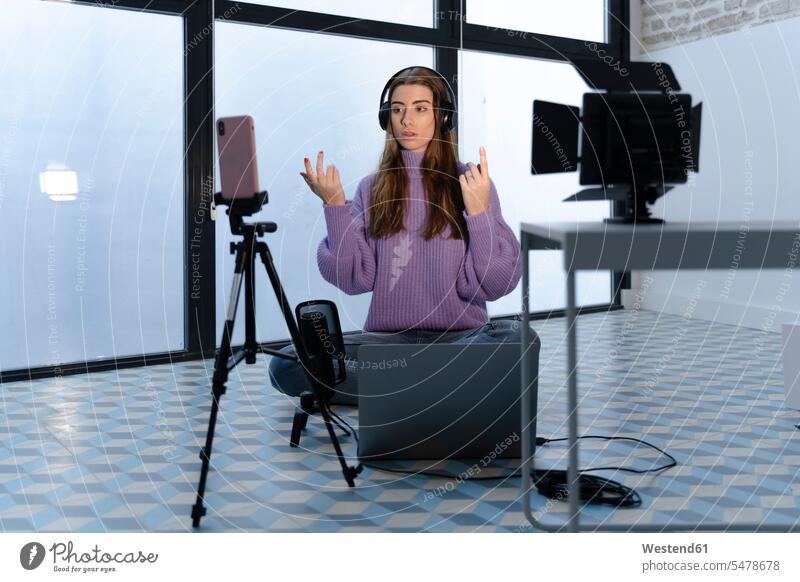 Portrait of young woman recording with laptop and smartphone in a studio Occupation Work job jobs profession professional occupation business life