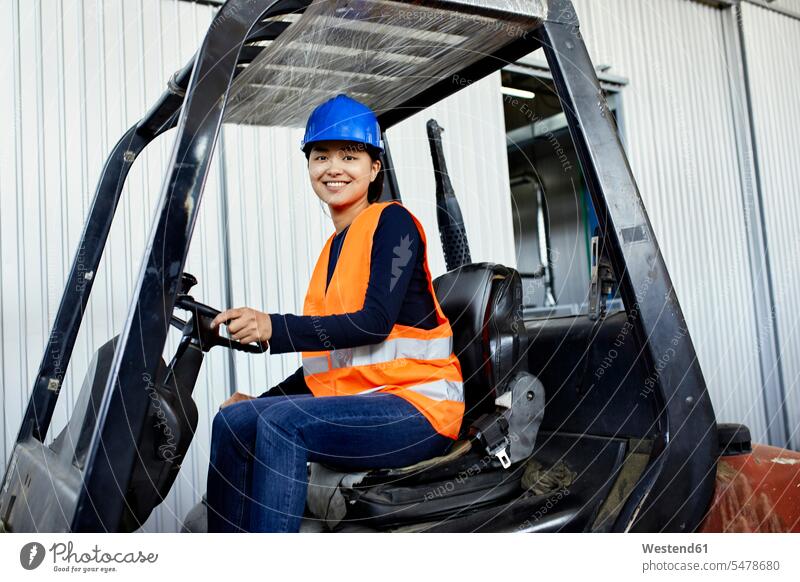 Portrait of confident female worker on forklift in factory portrait portraits confidence female workers forklifts forklift truck forklift trucks factories