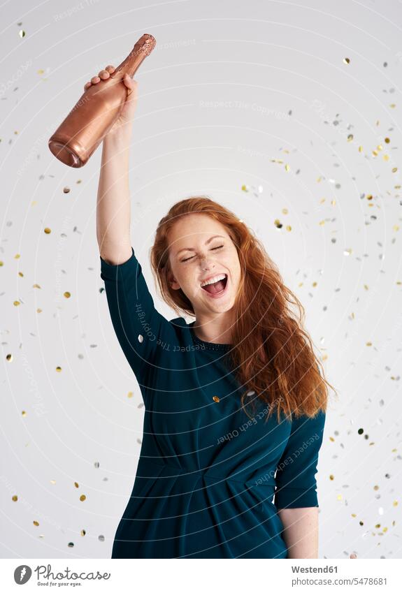 Portrait of happy young woman with bottle of champagne at shower of confetti Champagne Bottle Champagne Bottles females women portrait portraits happiness paper