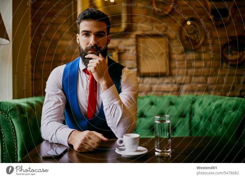 Portrait of fashionable young man sitting on couch in a cafe portrait portraits men males Seated settee sofa sofas couches settees Adults grown-ups grownups