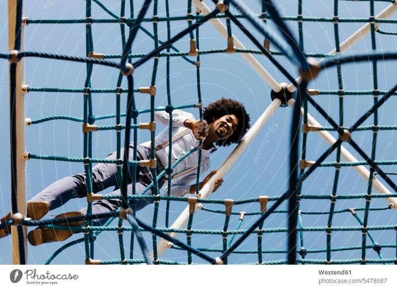 Laughing man standing on edge of jungle gym looking down view seeing viewing Jungle gym Jungle gyms men males laughing Laughter Adults grown-ups grownups adult