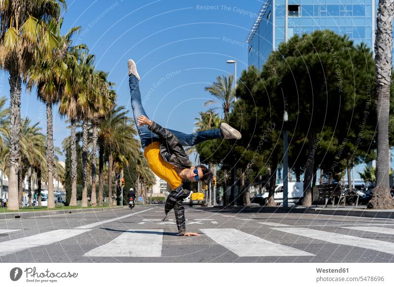 Spain, Barcelona, man in the city doing a handstand on the street leaning rested on playful effortless effortlessness easy leather jacket leather jackets