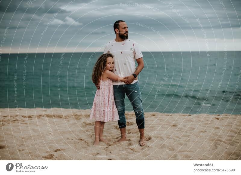 Daughter embracing father at beach color image colour image outdoors location shots outdoor shot outdoor shots dusk evening twilight in the evening Late Evening