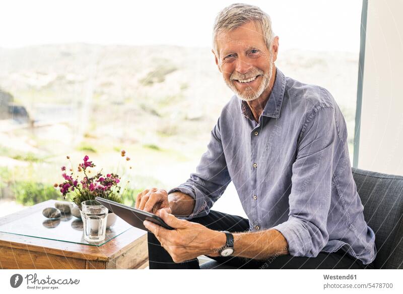 Portrait of smiling senior man using tablet at home confident Contented Emotion pleased smile Emotions Feeling Feelings Sentiment Sentiments optimism