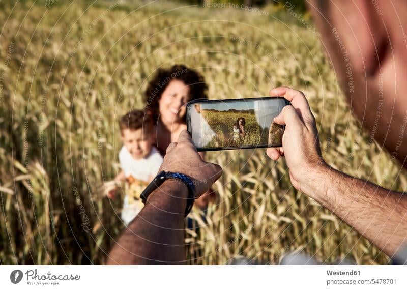 Close-up of man photographing mother and son with smart phone in farm color image colour image Spain leisure activity leisure activities free time leisure time