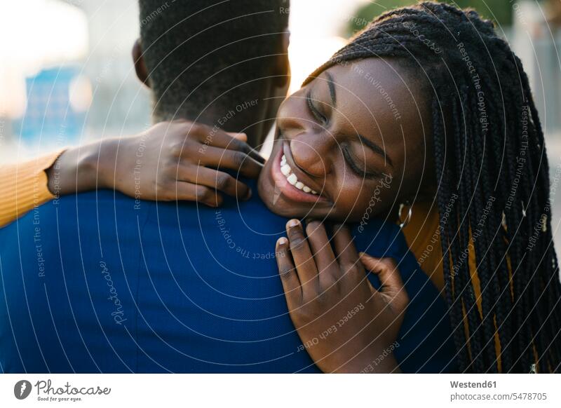 Smiling teenage girl with eyes closed hugging boyfriend outdoors color image colour image location shots outdoor shot outdoor shots day daylight shot