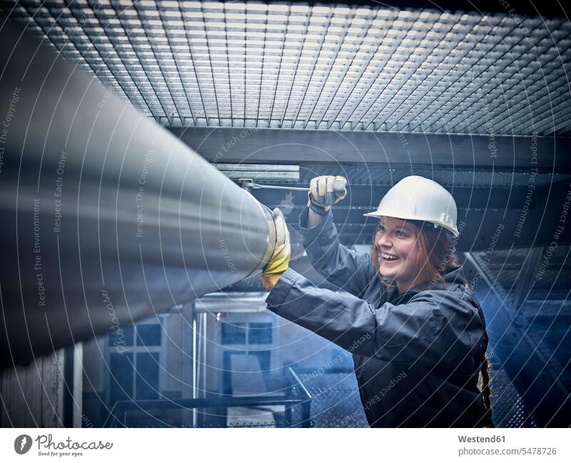 Happy craftswoman wearing hard hat working at pipe human human being human beings humans person persons caucasian appearance caucasian ethnicity european 1