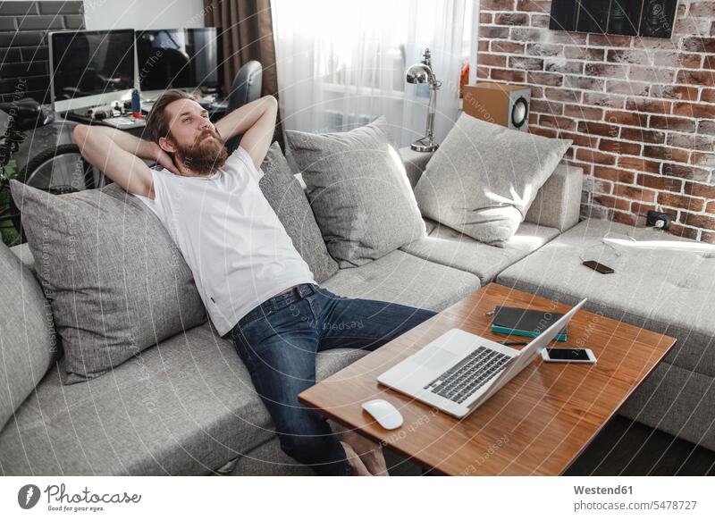 Smiling man relaxing on the couch at home men males settee sofa sofas couches settees smiling smile relaxation relaxed Adults grown-ups grownups adult people