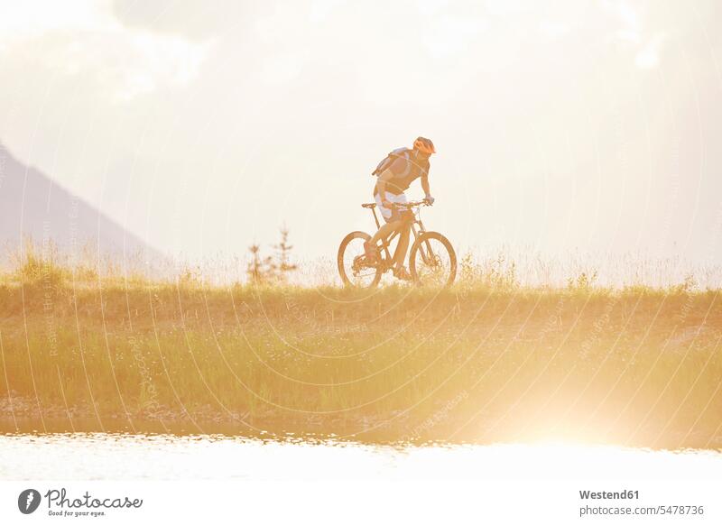 Austria, Tyrol, mountainbiker in the evening light mountain biker Mountain Bikers riding bicycle riding bike bike riding cycling bicycling pedaling driving