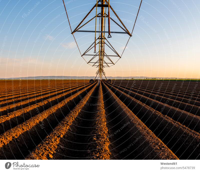 Agricultural machinery in ploughed field against sky during sunset color image colour image outdoors location shots outdoor shot outdoor shots sunsets sundown
