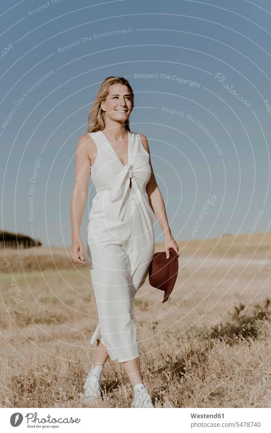 Female traveller with straw hat go going walk hold hike free Liberty free time leisure time Distinct individual fashionable on the go on the road on the way