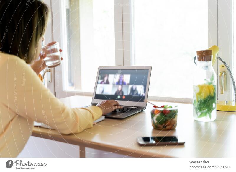 Young female professional on video conference with colleagues through laptop while working at home color image colour image Spain indoors indoor shot
