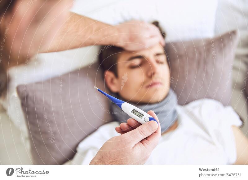 Close-up of doctor examining patient's temperature sleeping on bed at home color image colour image Germany indoors indoor shot indoor shots interior