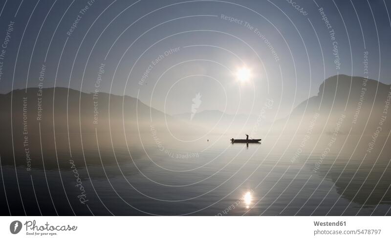 Austria, Mondsee, View of fishing boat in lake with foggy morning lake Mondsee clear sky copy space cloudless reflection reflections reflexions silhouette