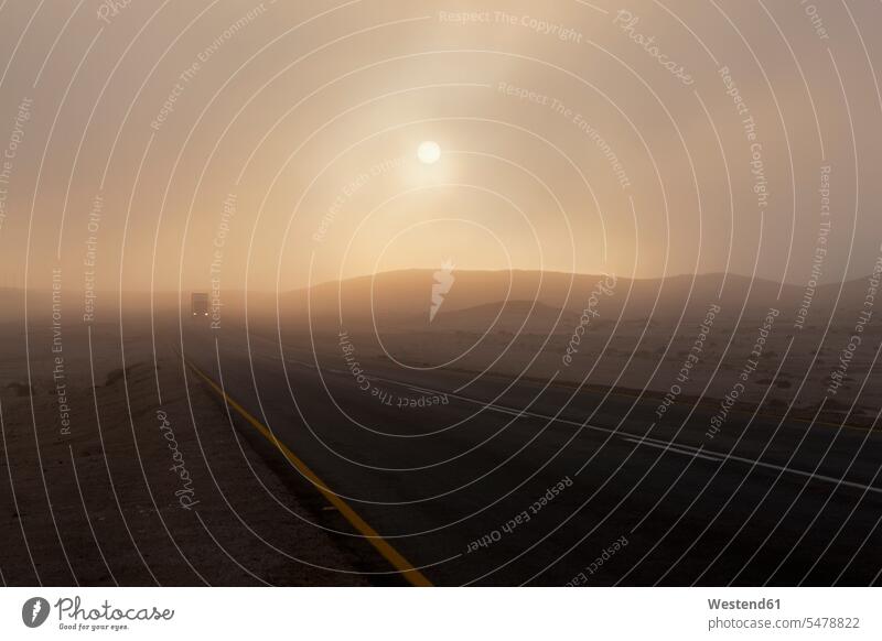 Africa, Namibia, Namib Desert, Swakopmund, View of vehicle on foggy road at dawn Republic of Namibia illuminated lit lighted color image colour image head light