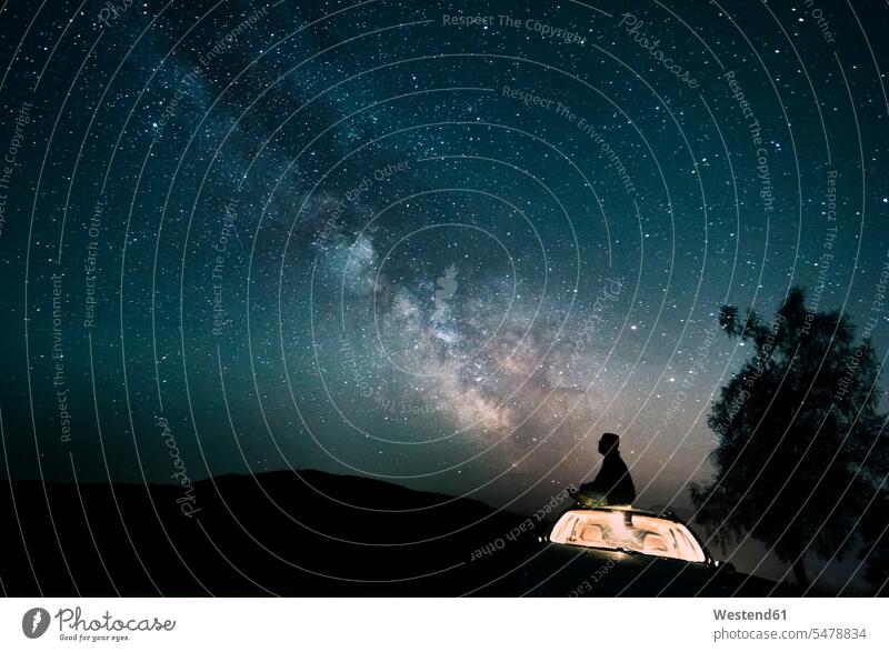 Austria, Mondsee, silhouette of man sitting on car roof under starry sky Starscape watching looking looking at silhouettes universe outer space view seeing