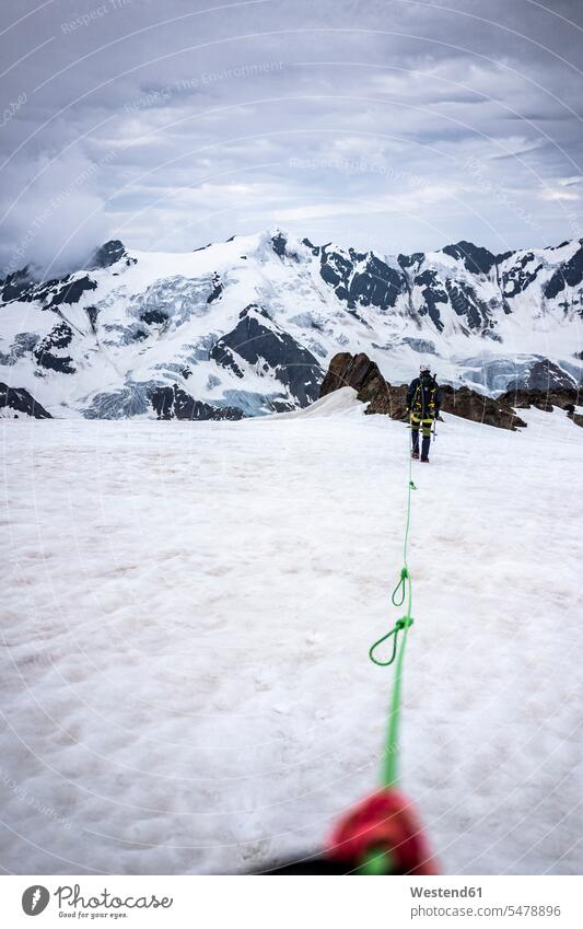 Mature man with rope walking on snow covered landscape against sky, Stelvio National Park, Italy color image colour image National Parks nature reserve
