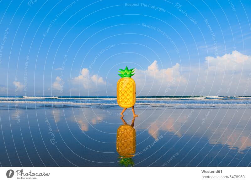 Woman with pineapple float walking at beach color image colour image outdoors location shots outdoor shot outdoor shots day daylight shot daylight shots