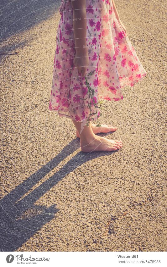 Girl standing barefoot on road holding flower Summer Dress Summer Dresses leisure free time leisure time evening caucasian caucasian ethnicity