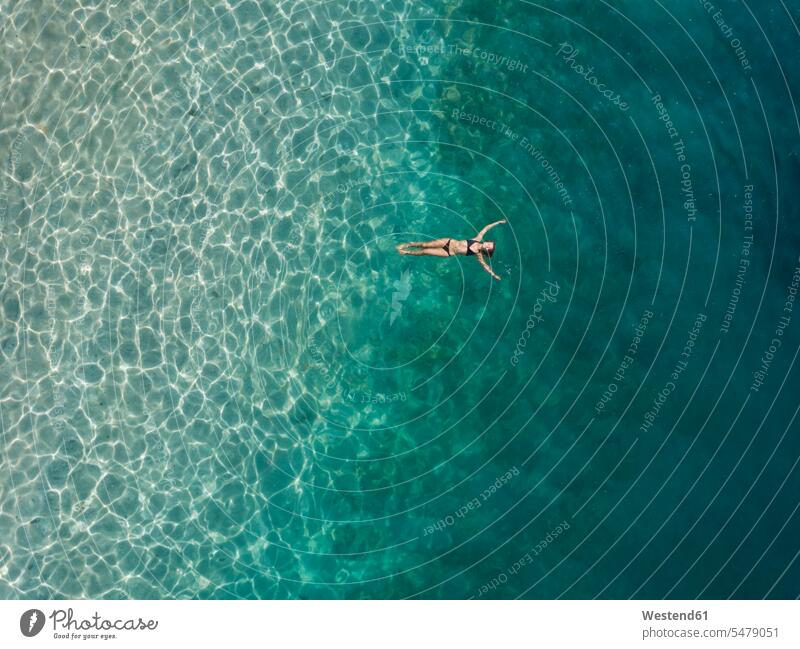 Woman floating in the sea, Gili Air, Gili Islands, Indonesia swim wear bikinis bathe Taking A Bath seasons summer time summertime summery light free Liberty