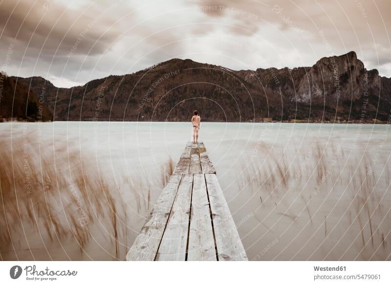 Austria, Lake Mondsee, Rear view of nude man standing on pier aspiration yearning Crave Craving aspirations wistful longing Solitude seclusion Solitariness