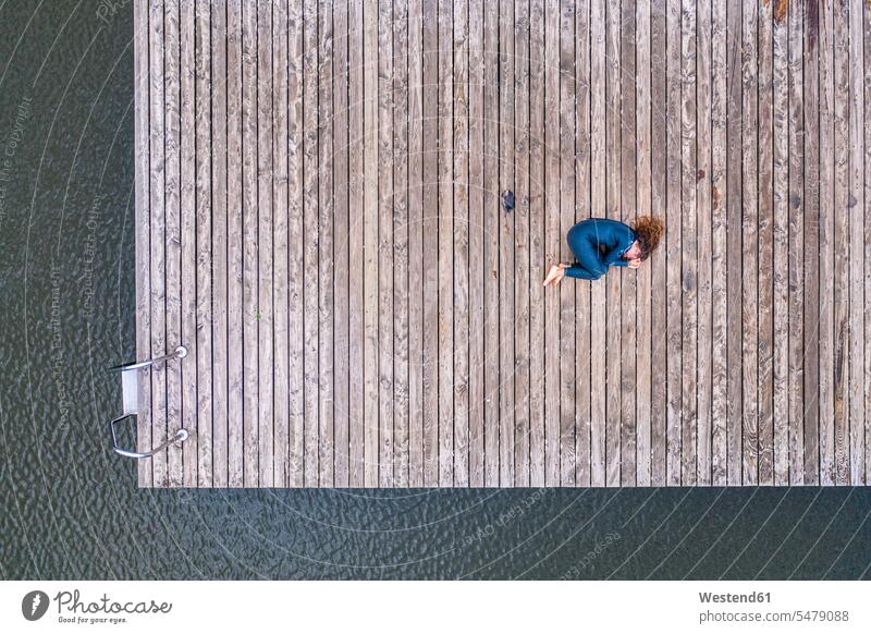 Aerial view of a young female triathlete lying on jetty at a lake human human being human beings humans person persons caucasian appearance caucasian ethnicity