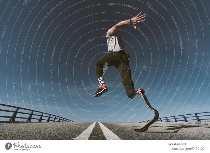 Disabled athlete with leg prosthesis exercising on a road exercise practising train training run jumps Leaping practice practise apace quick rapidity rapidness